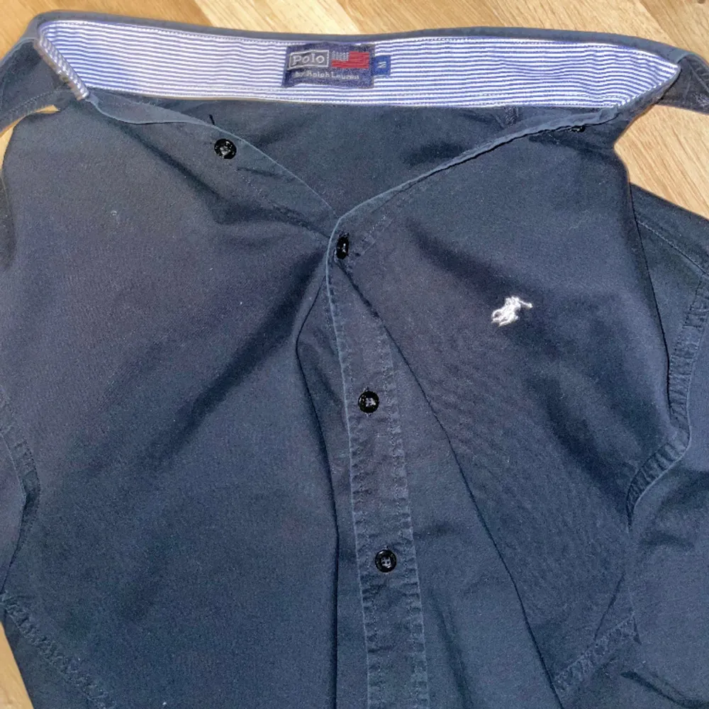 Tjena, säljer nu en svart Ralph Lauren skjorta med mörkblå ton i strl M, men passar S. Armar och krage är ljusblå, vit randig på insidan vilket ger en snygg detalj om man gillar uppvikta ärmar. Skjortan är i väldigt bra skick och vårt pris 329kr. Skjortor.