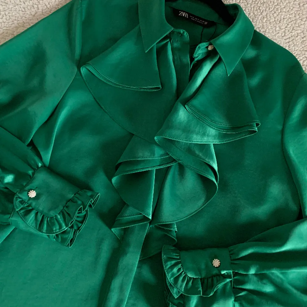Otroligt vacker blus från ZARA i en smaragdgrön färg med volanger och vita pärlknappar. Aldrig använd. Ny utan tags. Utan anmärkningar.. Blusar.