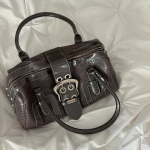 Väska - Superfin vintage väska från GUESS, köpt på Sellpy för 800kr. Missfärgade fläckar på insidan av väskan men inget som syns utifrån. Den har också en repa (se bild två) men det är inget man tänker på. Säljer då den ej kommer ej till användning. 