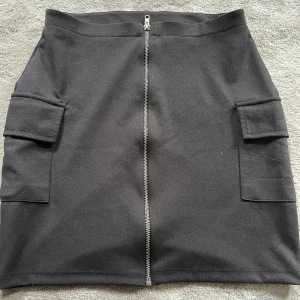 Svart kjol - Svart kjol i bra skick. Använd fåtal gånger. Fickor på båda sidor och dragkedja i mitten. 