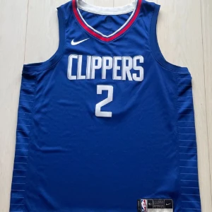 LA Clippers Basketlinne/Jersey - Los Angeles Clippers Swingman Jersey med Kawhi Leonard på ryggen (#2). Köpt sommaren 2022 för 999 kr och har använts sparsamt och är därför i gott skick. 