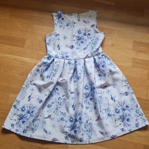 Barn klänning - Blå med blommor. Ej andvänd Ska passa för ungefär 13-14år men funkar som s-m