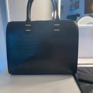 Svart handväska - Svart handväska som får plats med mycket, bra skick se bilder för defekter som finns på spännerna.