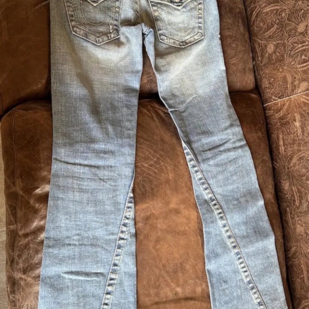Säljer dessa sjukt snygga true religion jeans i en bootcut modell med super låg midja. Är helt kär i dessa jeans så är jätte ledsen att de tyvärr inte passar mig längre. midjemåttet:37 cm, innerbenslängden: 79 cm. Har inga bilder på då de ej passar.💗. Jeans & Byxor.