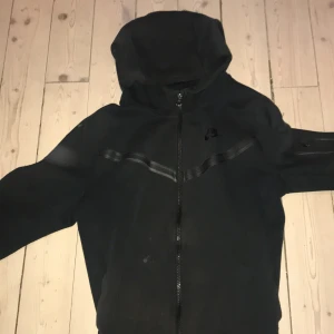 Nike tech svart - Säljer svart nike tech i storlek XL i barn. Har en liten missfärgning på vänstra sträcket annars är det bra skick. 