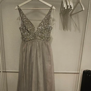 Glittrande festklänning - Fotlång fin klänning i skirt material, lager på lager i kjolen. 