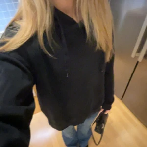 Svart hoodie - En svart hoodie. Har en vit färgfläck på ena armen.