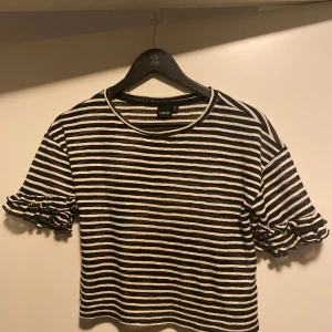 Randig kortärmad topp med volang ärm från LMTD! - Jättefin randig topp i tunt material med volang ärm. Storken är ganska stor för att vara 146 /152 så passformen är mer som en XS.  Mycket bra skick!