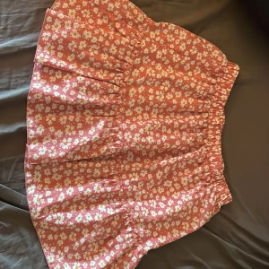 Rosa kjol med vita blommor - Kjolen är inte så lång den går ovanför knäna, använt några gånger men är i bra skick