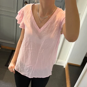 Rosa volangblus  - Rosa kortärmad blus med volanger från Bondelid. Storlek XS men passar även mig som brukar ha S och M. Fint skick. Använd gärna köp nu!