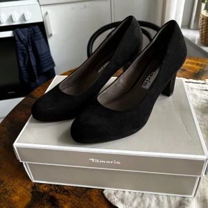 Svarta högklackade skor - Svarta klackskor ”Annie platform” av märket Tamaris i storlek 38.  Materialet är mjuk Suède på utsidan med några små lätta repor som endast är synliga från nära håll.  - Använda endast en gång men kommer tyvärr inte till användning längre.
