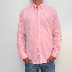Ralph Lauren  - Rosa Ralph Lauren skjorta i storlek 15,5 vilket motsvara ca L. Skjortan är i fint skick utan några skavanker. Modellen är 186 cm lång. Orginalpris ca 1500 kr och nu endast 499. 