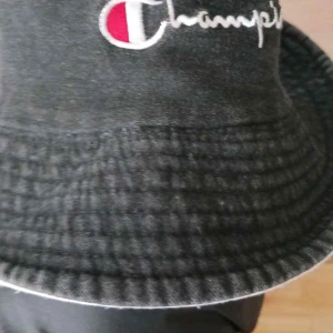 Champion hatt - Bully hat från Champion. Den här klassiska bullyhatten, eller bucket cap,Den perfekta accessoaren för din look. Bullyhatten kommer med en Champion-logotyp framtillSvart eller vit. Du kan välja.  Andvänd skick
