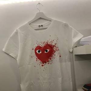 Säljer nu denna riktigt snygg CDG T-shirt. Den har en riktigt snygg design av CDG loggan med en snygg stänkande röd färg runt om kring sig. Den är helt ny har alldrig använt den. Det är bara att höra av sig vid frågor om T-shirten.