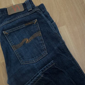 nudie jeans - säljer dessa jeans från nudie jeans med orangea detaljer i herrmodell. nypris 1400. dem är i väldigt bra skick. innerbenslängden är ca 79-80 cm och midjemåttet rakt över 41 cm. skriv vid frågor eller för fler bilder! 
