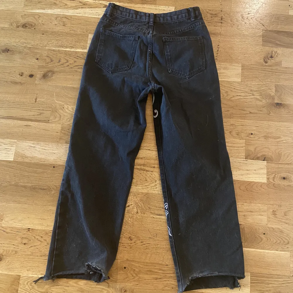 Ett par svarta coola baggy jeans med vitt tryck. Använda några gånger men ändå jättebra skick, lite slitna längst nere men det är inget man märker❤️. Jeans & Byxor.