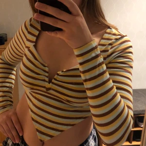 V-shaped tröja - Randig, långärmad tröja med V-shapes från Urban Outfitters 👔Färgerna är ljusblå, brun och gul. Har ej kommit till användning och är i gott skick