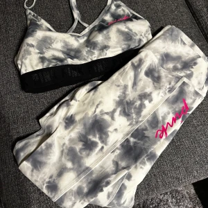 Träningset Marble från Victoria Secret - Oanvänt. Sport toppen har storlek L.  Träningsbyxorna storlek M. Köpt på Victoria Secret i New York. Setet är Marble. Grå och vit. Lampan går så det ser gult ut men det är det inte.