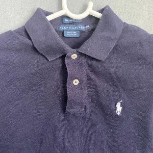 Ralph lauren Piké navy - Perfekt inför sommaren. Den har inte använts mer än 3 gånger.  Kvaliten är 9,5/10. Kan vara lite skrynklig p.g.a varit i garderoben under lång tidsperiod.            Org pris: 1200