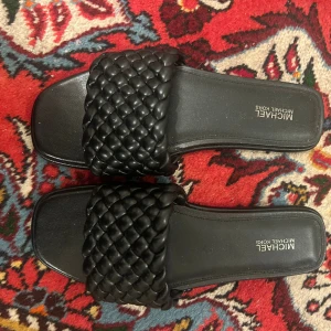 Svarta Michael Kors tofflor stl 7M - Svarta tofflor från Michael Kors i storlek 7M (37). Gott skick, knappt använda. Kostade 1000kr och säljs nu för 500kr. Jag kan mötas upp i Stockholm eller skicka skorna, men du står för frakten. 