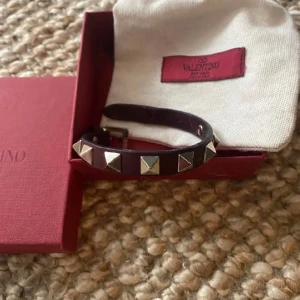 Valentino armband  - Säljer detta vinröda valentino armband med guldiga nitar! I använt men bra skick, enda defekten är synlig på sista bilden men inget man ser när man har på det. 1300 + frakt! Pris kan diskuteras vid snabb affär.😍