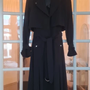 Detaljrik trench coat. - Lång och detaljrik trench coat. Metalldetaljer i grått.  Myckrt gott skick. 