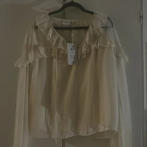 Blus med volanger - Säljer denna jättefina helt nya blusen med volanger från Vila! Säljer då den inte kommer till användning. Aldrig använd så helt ny! Storlek 34 men passar även 36! OBS välj gärna instabox som fraktalternativ! 