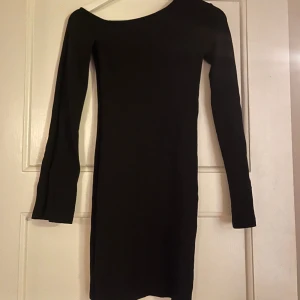 Klänning  - Tajt svart klänning med snedskuren hals och vida ärmar! Använd en gång. 