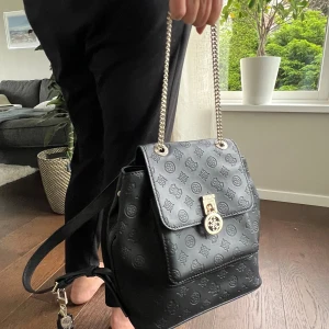 Guess ryggsäck  - Säljer denna svarta ryggsäck från Guess. Helt ny och aldrig använd! Ryggsäcken kan även bäras som en väska om så önskas (Se bild 1). Köpat för ca 1000 kr. Säljer enbart för att den inte kommer till användning. Köparen står för frakten.