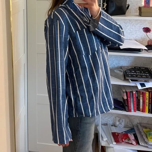 Randig blus - Blå, vitrandig blus. Mjukt material. En bröstficka.  Aldrig använd! Alldeles för stor till mig.  Storlek S enligt produkten. 