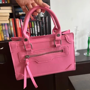 rosa väska - söt liten väska. Finns tillhörqnde axelremsband om man hellre vill ha den så! Använd endast en gång, därför är den i mycket bra skick :)