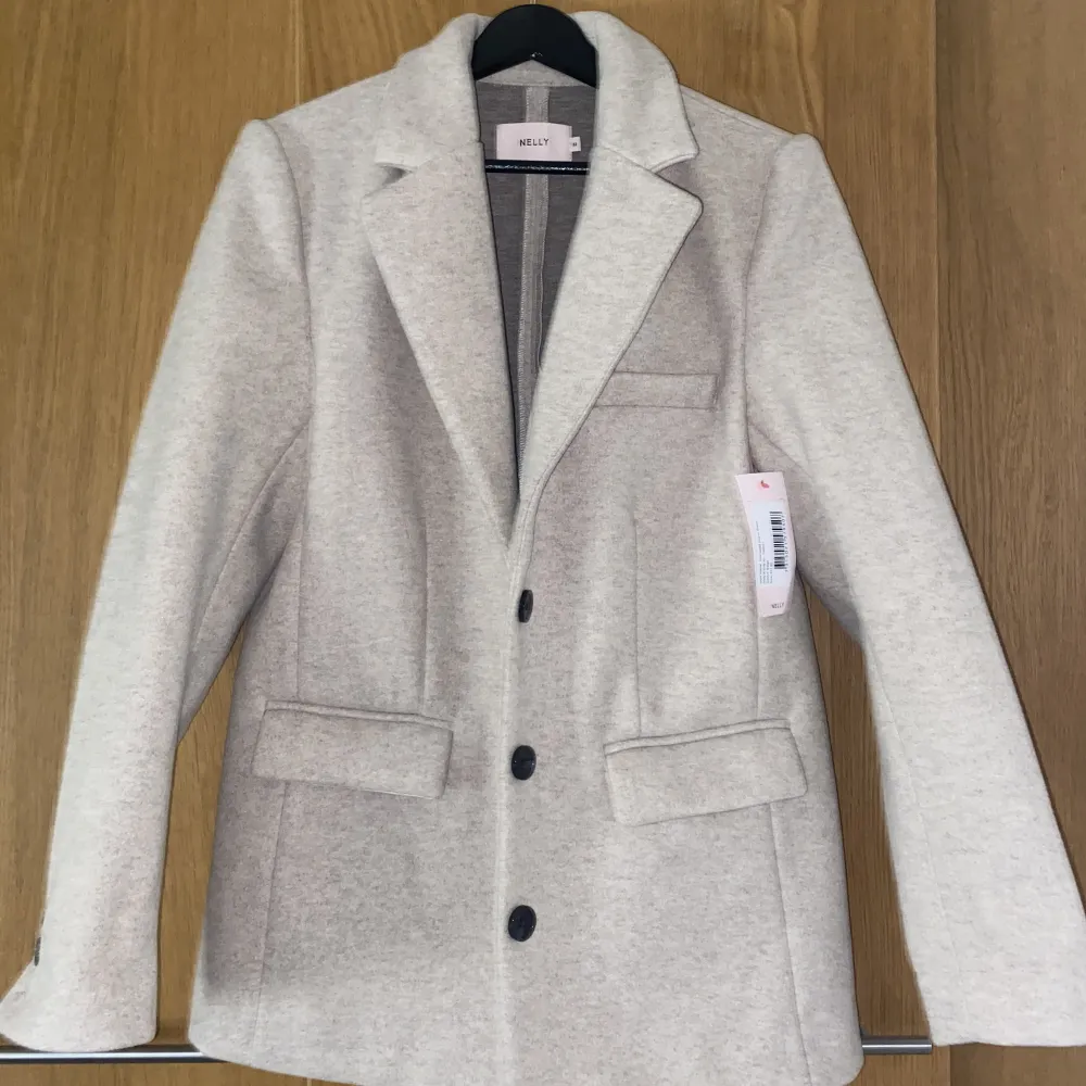 En beige varmare blazer från Nelly. Perfekt som jacka i höst och vinter. Helt oanvänd då den tyvärr var för stor för vad jag gillar. Prislappen kvar i storlek 32 men skulle mer säga det är en 34 då den är oversized. . Kostymer.