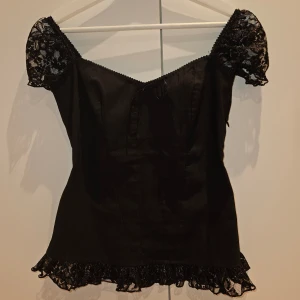 Topp - Så fin svart topp 🫶🏻 är lite korsettliknande och har spetsdetaljer samt en rosett framtill! Saknar lapp så vet inte märke, och är tyvärr för liten så kan inte visa bild på! Men hör av er vid frågor eller så 🤍