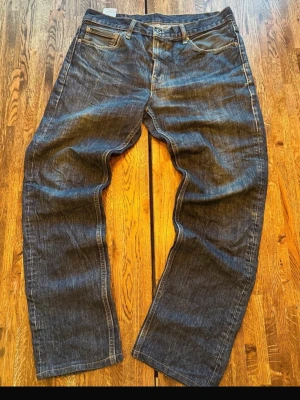 Levi's 511 blå jeans med klassisk look - Säljer ett par blå Levi's 511 jeans med klassisk femficksdesign och den ikoniska röda Levi's-lappen på bakfickan. Jeansen har en rak passform och är tillverkade i slitstarkt denimtyg. Perfekta för dig som gillar tidlös stil och vill ha ett par jeans som funkar till allt.