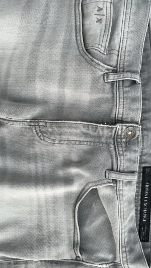 Ljusgrå jeans från Armani Exchange - Snygga ljusgrå jeans från Armani Exchange med klassisk femficksdesign och diskret logga på fickan. Jeansen har raka ben och är tillverkade i mjukt denimtyg som ger en avslappnad men stilren look. Perfekta för dig som gillar en modern och clean stil.