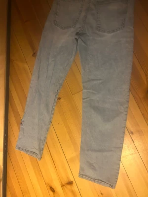 Ljusgrå raka jeans - Säljer ett par ljusgrå jeans med rak passform och klassiska bakfickor. Jeansen har hög midja och är tillverkade i ett mjukt denimtyg. Perfekta för en avslappnad och trendig look.