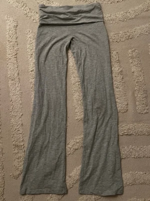 Grå yoga pants från Gina Tricot - Grå leggings från Gina Tricot med bootcut-ben och bred midjeresår. Mjukt och stretchigt material som sitter skönt på kroppen. Perfekta för en avslappnad och trendig look.