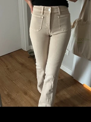 Beiga raka jeans från Mango - Snygga beiga jeans från Mango med raka ben och hög midja. Jeansen har klassiska fem fickor, bälteshällor och stängs med knapp och dragkedja. Perfekta för en clean och stilren look. Jeansen är sprättade så att dem passar mig som är 172!