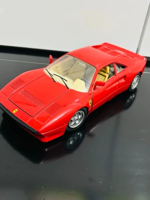 Röd Ferrari modellbil i metall  - Säljer en detaljerad röd modellbil av Ferrari i metall med svarta och gula detaljer. Bilen har realistiska fälgar, genomskinliga fönster och beige inredning. Perfekt för samlare eller som dekoration till rummet.