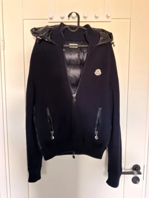 Moncler cardigan  - Säljer min extremt exklusiva och eftertraktade Moncler cardigan. Modellen är Moncler maglione cardigan i färgen marinblå. Detta är en extremt sällsynt modell som inte längre tillverkas och säljs av Moncler, och en av de få faktiskt äkta på marknaden. Nypris då var 14 000:- mitt pris är endast 5499:- finns väldigt få tecken på användning, otroligt bra skick! Storleken är L men sitter mer som en S/M
