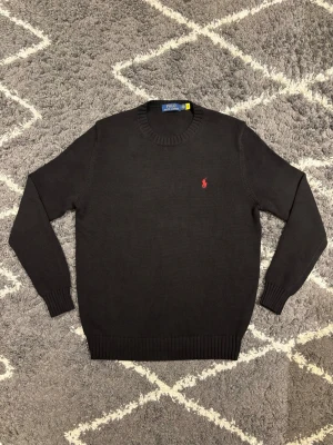 Polo Ralph Lauren tröja  - Svart stickad tröja från Polo Ralph Lauren i skönt bomullskvalitet. Röd pony på bröstet. Stilren och tidlös. Storlek S. Jag är 180cm och den passar mig perfekt.