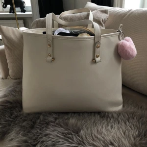 Vit weekendbag - Rymlig weekendbag,vit med guld detaljer. Använd några gånger. Lite repor på handtagen. 40x31
