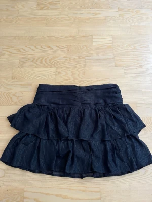 Mörkblå volangkjol - Snygg mörkblå kjol med volanger. Kjolen har två lager volanger som ger en cool och lekfull look. Perfekt att matcha med en crop top eller stickad tröja för en trendig outfit.