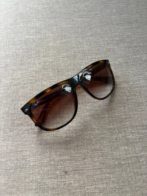 Bruna pilotbågar från Ray-Ban - Snygga solglasögon från Ray-Ban med klassiska pilotbågar i brunmelerad plast och tonade bruna glas. Perfekt accessoar för soliga dagar och ger en cool retrovibe till din outfit.