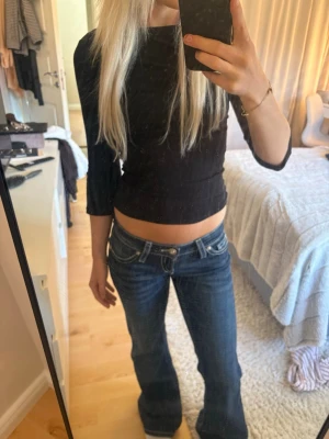 Mörkblå bootcut jeans med låg midja - Säljer ett par mörkblå bootcut jeans med låg midja och klassiska fem fickor. Jeansen har snygga kontrastsömmar och en lätt utsvängd passform nertill. Perfekta för en avslappnad och trendig look.
