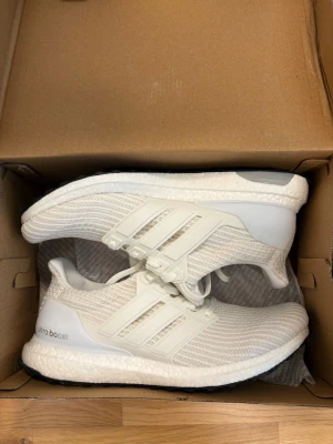 Adidas Ultraboost - Säljer ett par fräscha vita Adidas Ultraboost sneakers. De är helt nya och box mm ingår. Storlek 44. Pris går att diskutera vid snabb affär. MVH