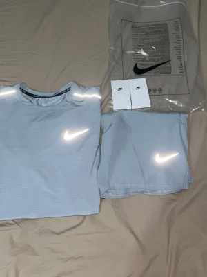 Nike ljusgrått träningsset herr - Säljer ett ljusgrått träningsset från Nike med t-shirt och shorts. Båda plaggen har reflekterande Nike-logga och är tillverkade i ett lätt, snabbtorkande material som passar perfekt för löpning eller gym. Setet har en sportig och modern look.