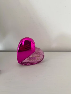 Cuore Pink parfym hjärtformad rosa - Säljer en söt parfym från Flor De Mayo, modellen Cuore Pink. Flaskan är hjärtformad i genomskinligt rosa plast med guldfärgad spray och ett matchande rosa lock. Perfekt för dig som gillar färgglada och lekfulla dofter. INTE ANVÄND