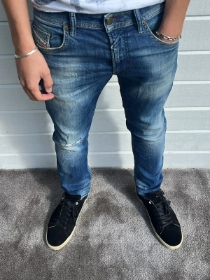 Diesel jeans blå  - Tjena! Riktigt snygga diesel jeans säljes! Snygg tvätt med snygga detaljer och slitningar! Modellen på bilden är 183cm och väger 68kg. Passformen är slim och har storleken W31/L32. 98% bomull och 2% elastan. Hör av dig!