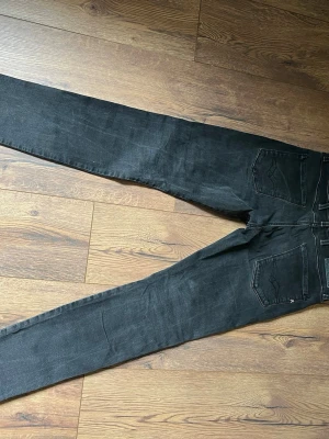 Svarta Replay jeans, - Säljer ett par svarta jeans från Replay med raka ben och klassisk femficksmodell. Jeansen har diskreta slitningar och är tillverkade i en stretchig bomullsblandning för skön passform. Perfekta för dig som gillar en clean och stilren look. W 30 l 32
